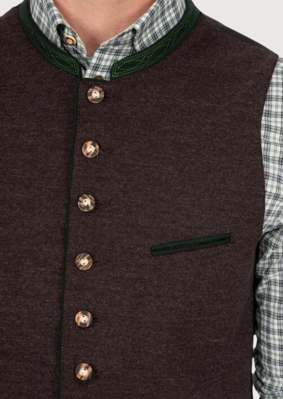 Man in classic Bavarian vest with green accents and leather trousers for Oktoberfest

