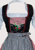 Black check Dirndl dress for women featuring a black embroidered bodice, white puff sleeve blouse, gingham apron, and authentic Bavarian Oktoberfest styling.