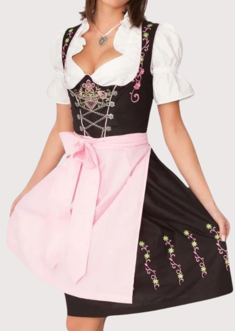 Women wearing black traditional dirndl dress with pink apron, floral embroidery, lace-up bodice, and classic Bavarian alpine folk styling.