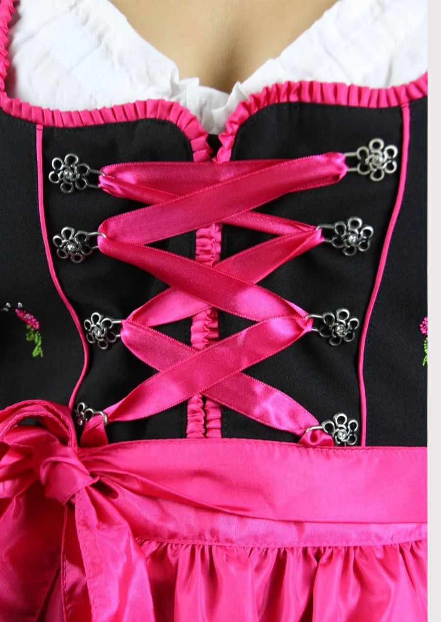 Women's black Dirndl dress with a vibrant pink satin apron, lace-up bodice, white blouse, and traditional Bavarian Oktoberfest styling.