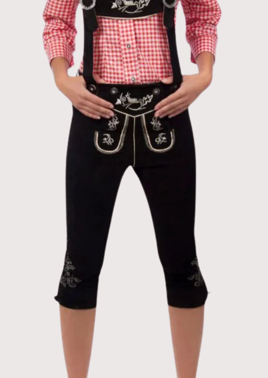 Black women’s traditional Bundhosen trousers with suspenders, ornate alpine embroidery, and classic Bavarian folkwear styling.