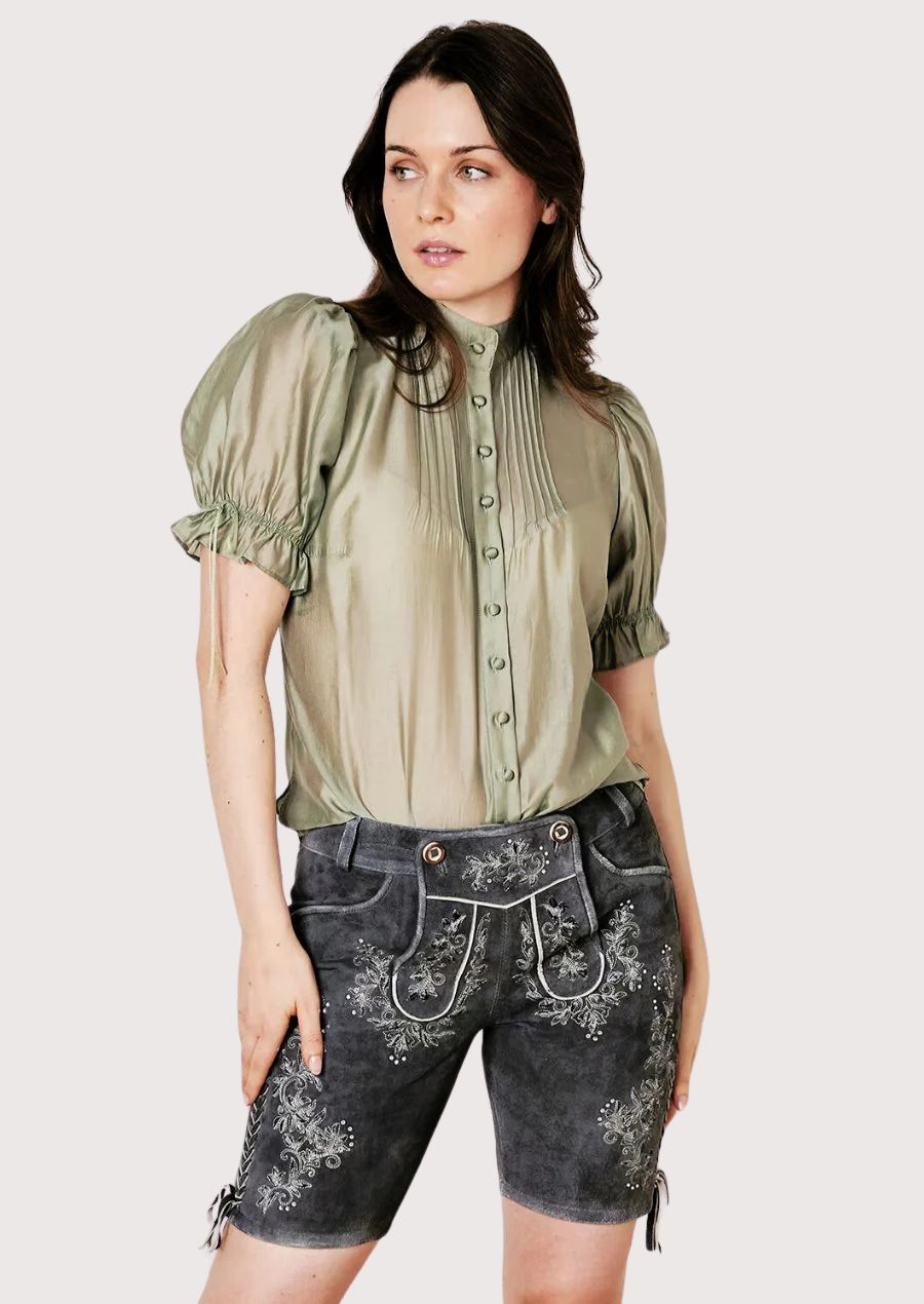 Modern alpine women’s lederhosen styled with decorative embroidery and soft green top