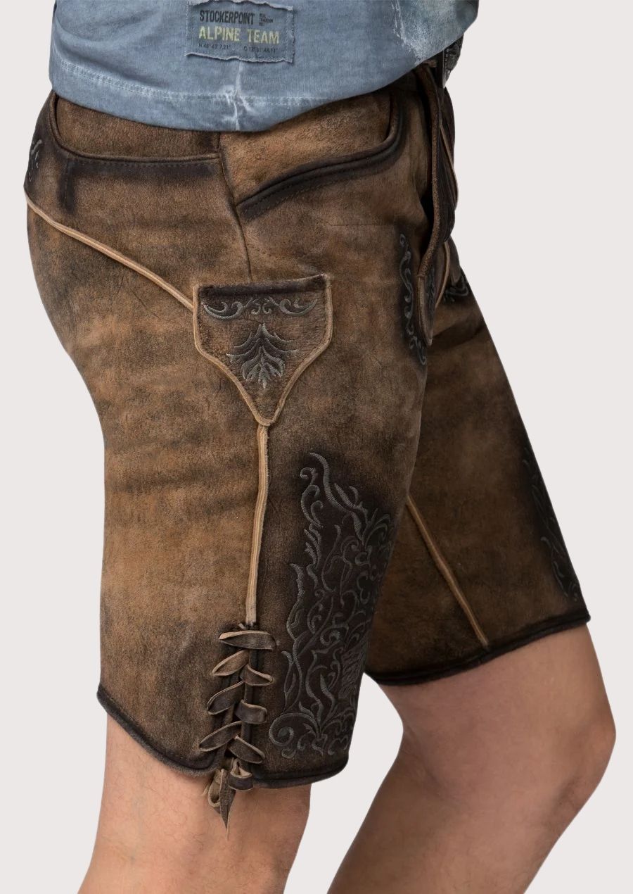 Traditional lederhosen crafted from brown suede with gothic-inspired embroidery and engraved buckle