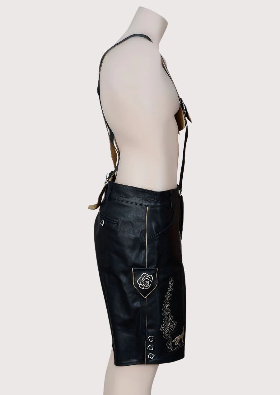 Authentic black leather lederhosen featuring deer motif embroidery, suspenders, and Alpine-inspired craftsmanship