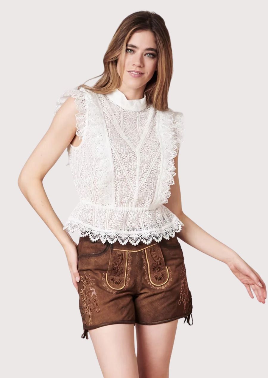 Romantic Alpine lederhosen for women featuring embroidered suede shorts and an elegant lace-trimmed heritage blouse.