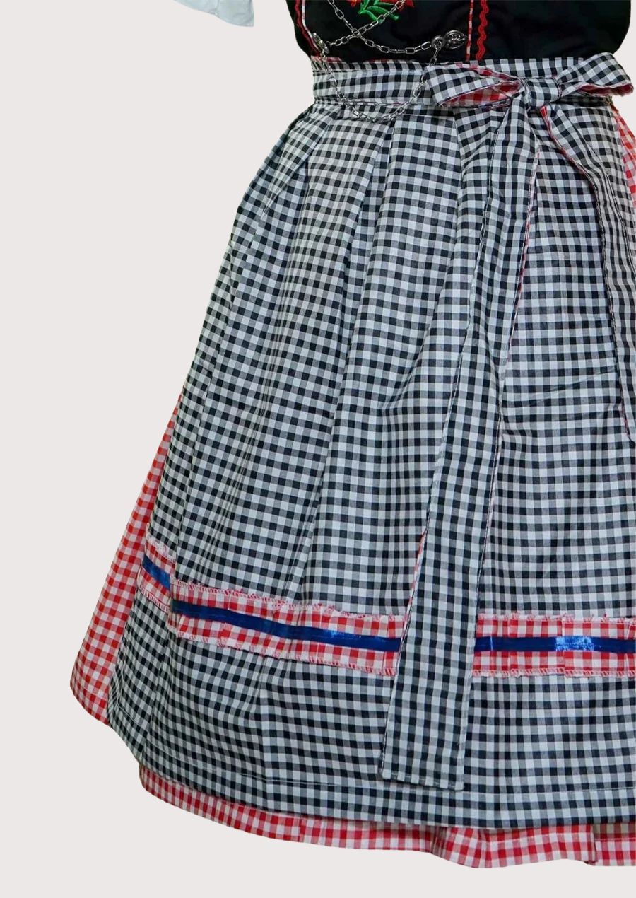 Traditional German Dirndl dress featuring red gingham side panels, black embroidered bodice, white blouse, and checkered apron for Oktoberfest celebrations.