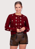 Women's brown suede lederhosen shorts paired with a red embroidered Alpine cardigan and traditional Bavarian styling.