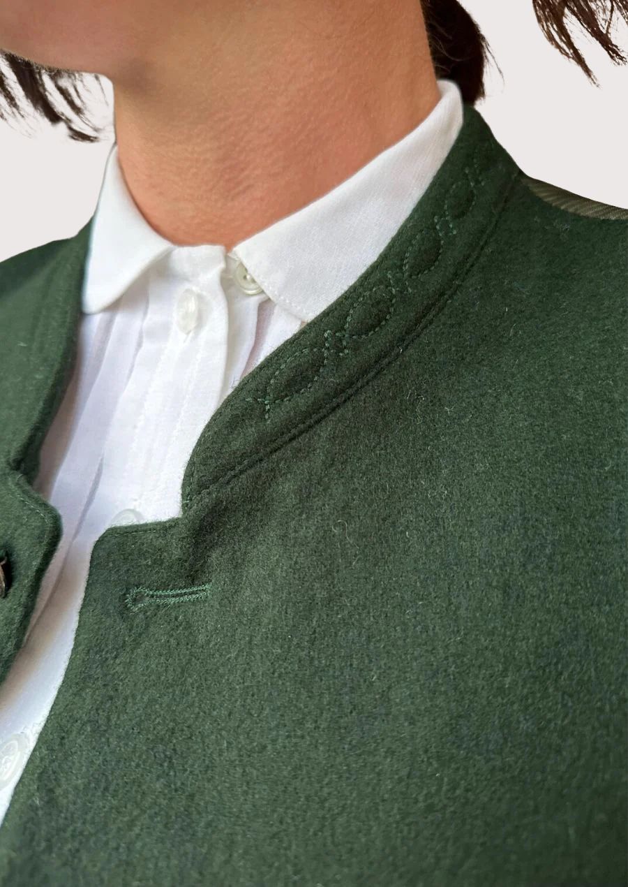 Alpine style women’s green vest paired with white shirt.