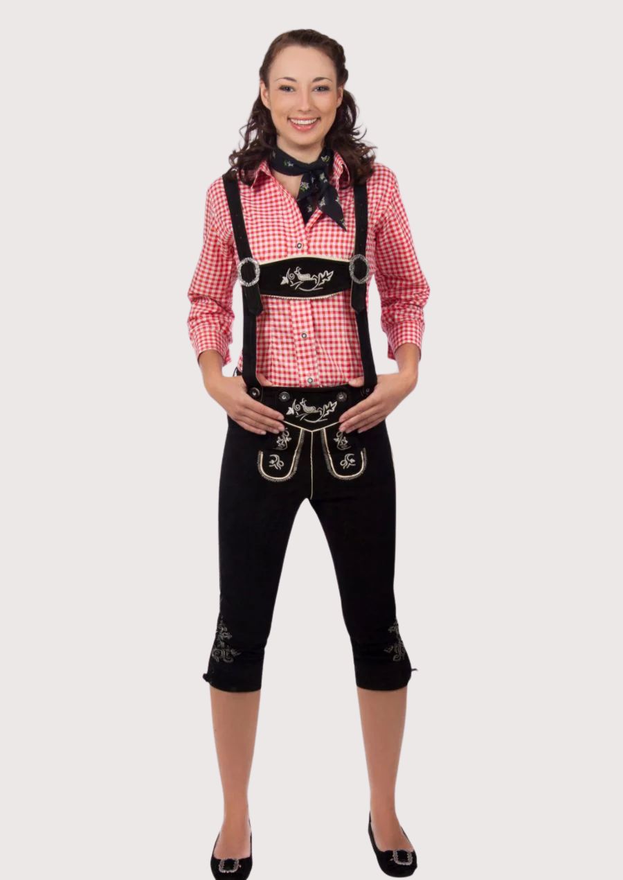Women's black knee-length lederhosen with suspenders, silver embroidery, red gingham Trachten shirt, and Alpine scarf.