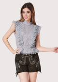 Women's black embroidered lederhosen shorts paired with a gray lace blouse, blending Alpine heritage and modern elegance.