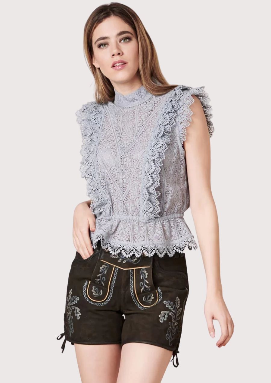 Woman wearing grey lace blouse paired with dark embroidered traditional lederhosen