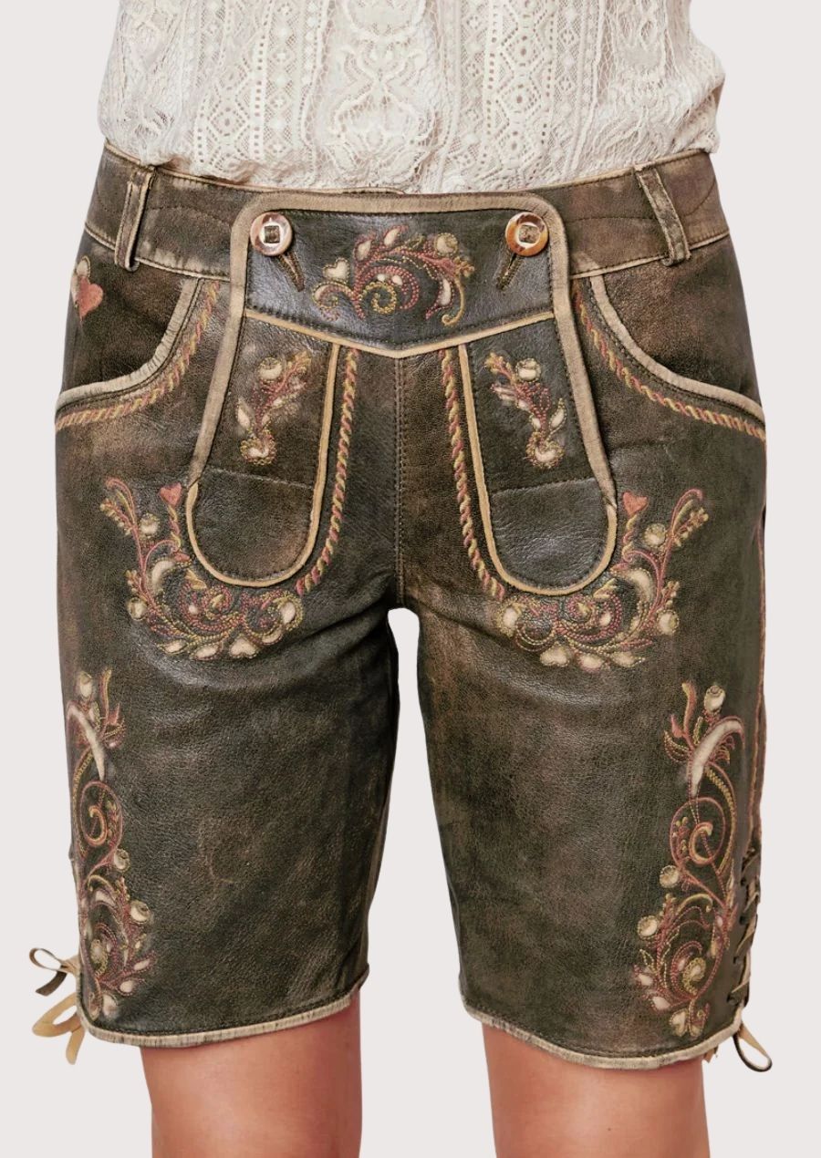 Woman wearing elegant lace blouse paired with embroidered traditional lederhosen shorts